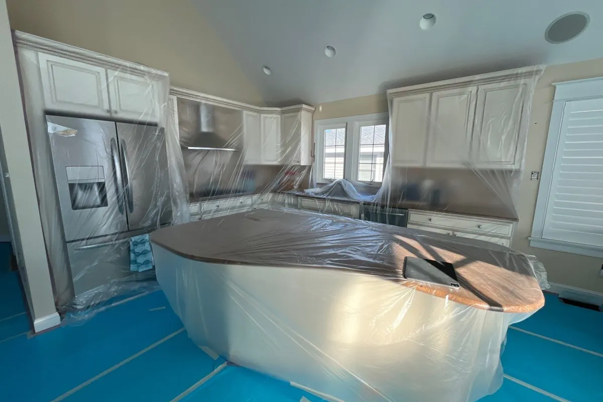 Kitchen wrapped in protective plastic with floor protection during repair prep